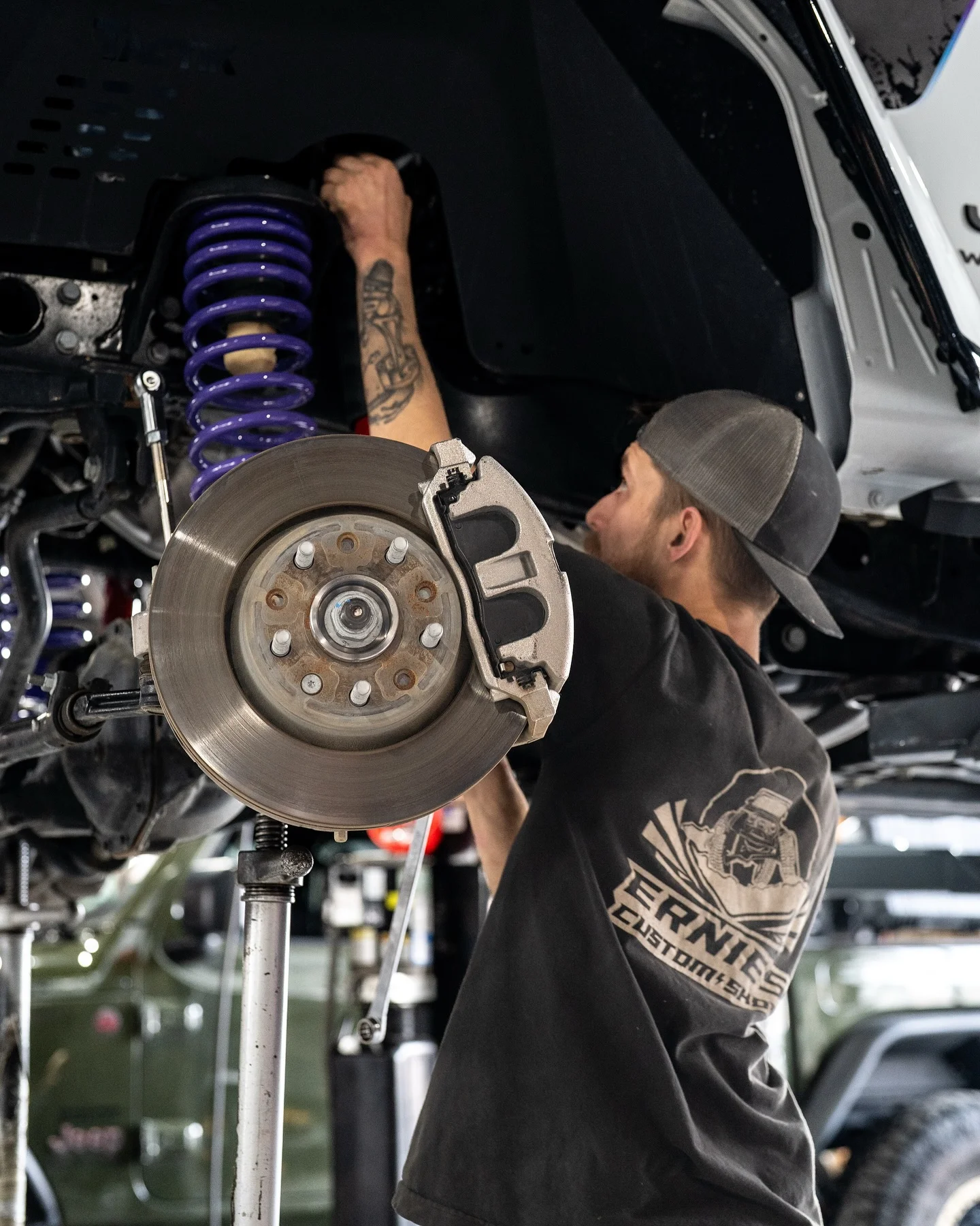 An Ernie's Custom Shop technician working on a hub and coilover